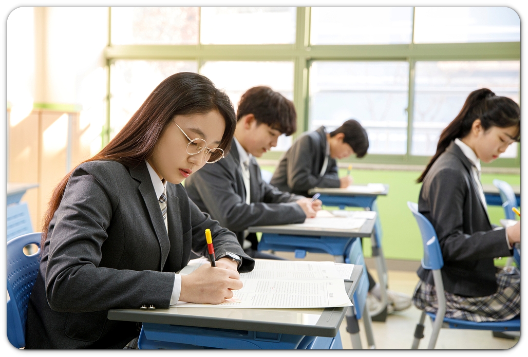 교실에서 책을 보며 필기하는 학생